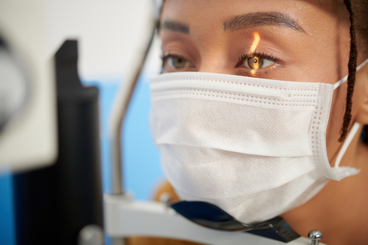 Close-up image of young woman having back of the eye examined with help of slit lamp. Complete guide for laser eye surgery.